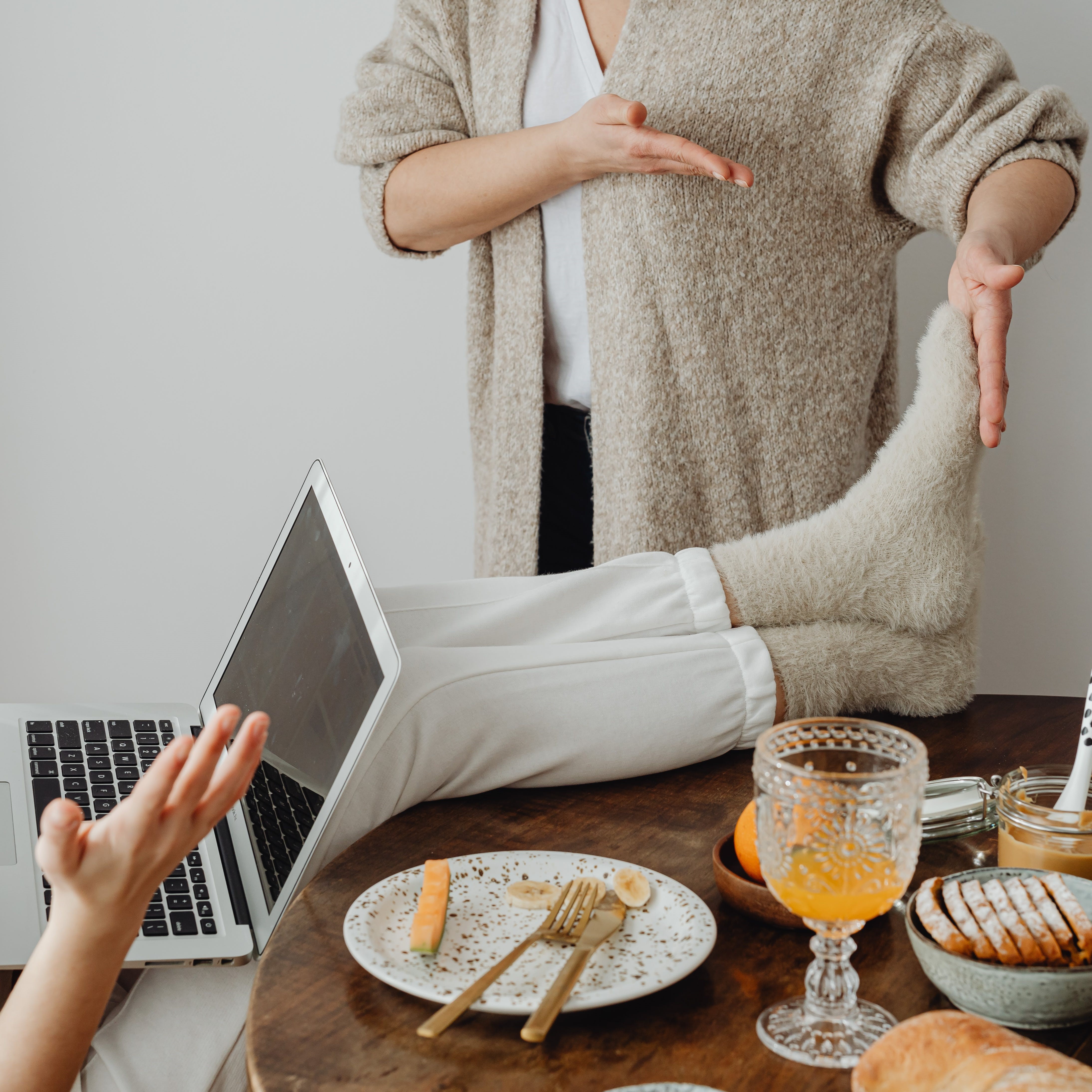 a person with a laptop wearing fuzzy socks they put on the table much to the chagrin of another person who is referencing their feet in a dispute.