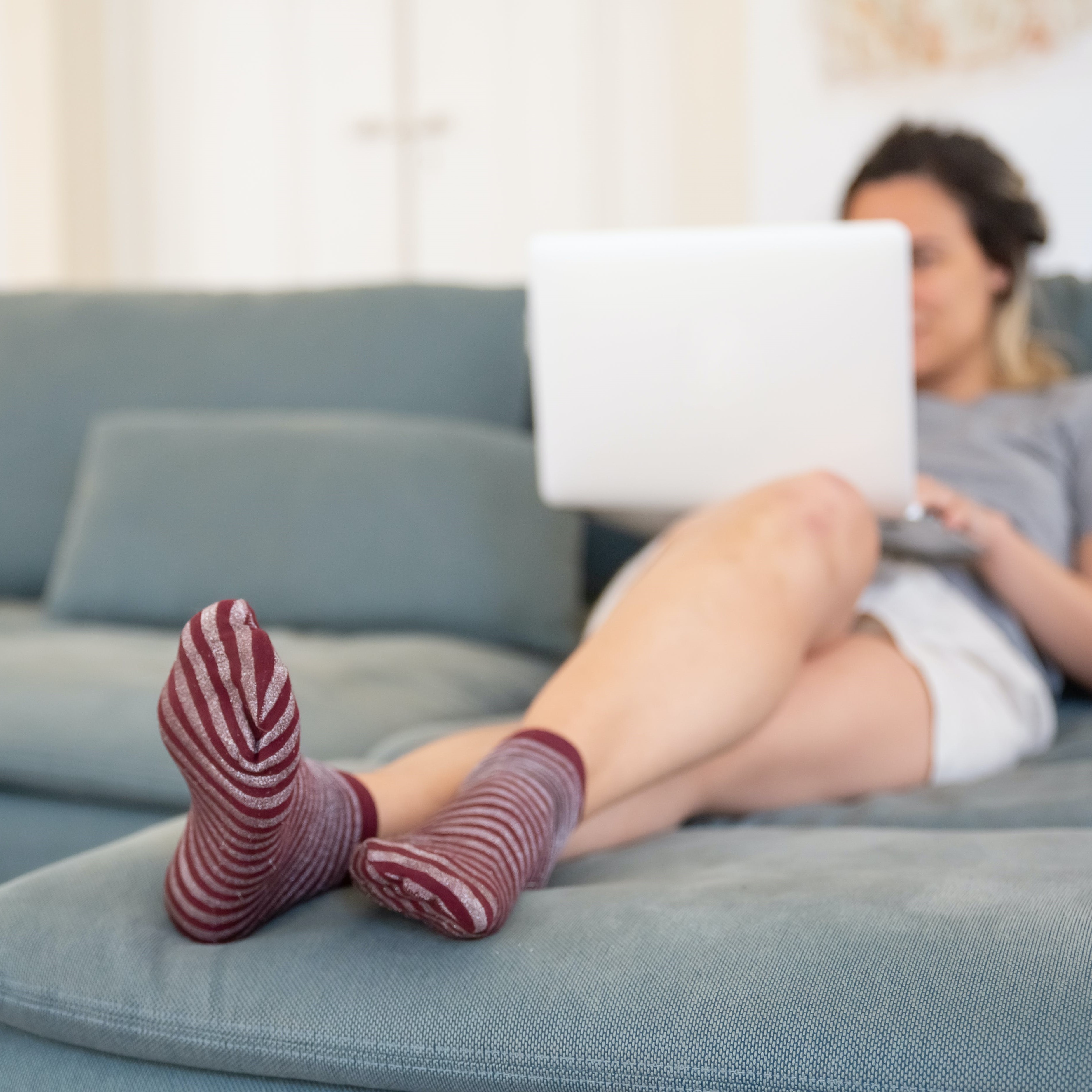 a person with stripy stocks uses a laptop on the sofa with the socks mostly in frame